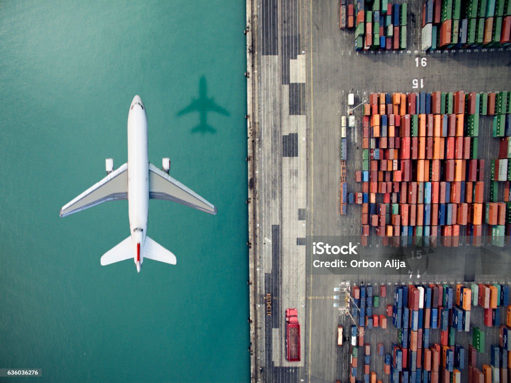 Airplane flying over container port Freight Transportation Stock Photo