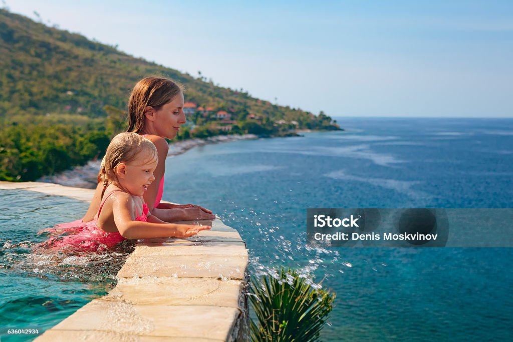 Mother with child swim with fun in infinity pool Happy family. Mother with baby swim with fun in outdoor infinity pool, relax at poolside, look at sea beach. Healthy lifestyle, active parent, people recreational activity on summer holiday with child Family Stock Photo