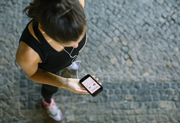 woman monitoring her workout progress on fitness app - ouvindo batidas do coração imagens e fotografias de stock