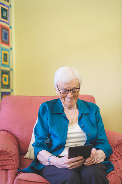 istock Elderly woman reading on a digital tagblet in her 636044702