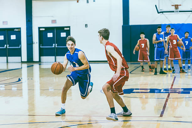 High school basketball player driving to the hoop A male high school basketball player is driving to the hoop to score during a competative game secondary school activities stock pictures, royalty-free photos & images