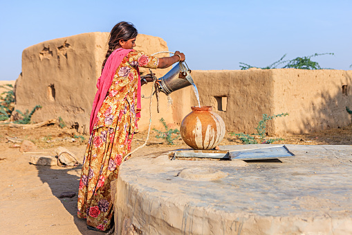 Indian woman collecting pure water from the well. Collecting and carrying water are women's responsibilities in India. Rajasthani women often walk long distances through the desert to bring back jugs of water that they carry on their heads . Thar Desert, Rajasthan. India.http://bhphoto.pl/IS/rajasthan_380.jpg