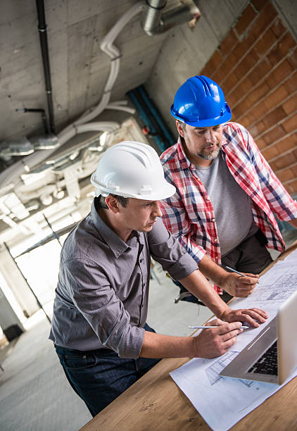 istock Architect And Construction Worker Reviewing Blueprint Together 636057952