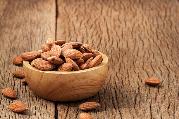 istock Closeup almonds kernels in wooden bowl with hemp sack on 636058844