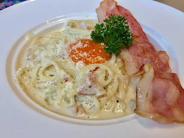 Spagetthi carbonara Serve with yolk bacon and parmesan cheese on white plate