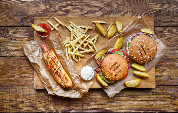 фаст-фуд отнять вид сверху. гамбургер, хот-дог и картофель фри - hot dog hamburger burger grilled стоковые фото и изображения