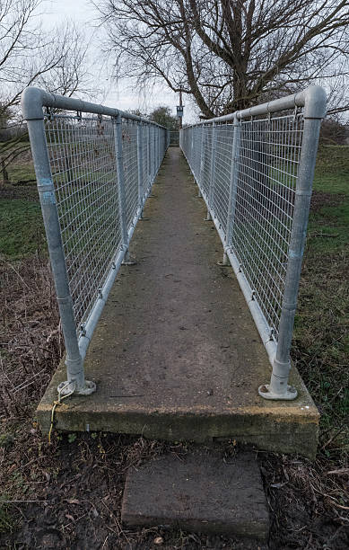 istock Narrow public footpath seen over a river canal 636069658