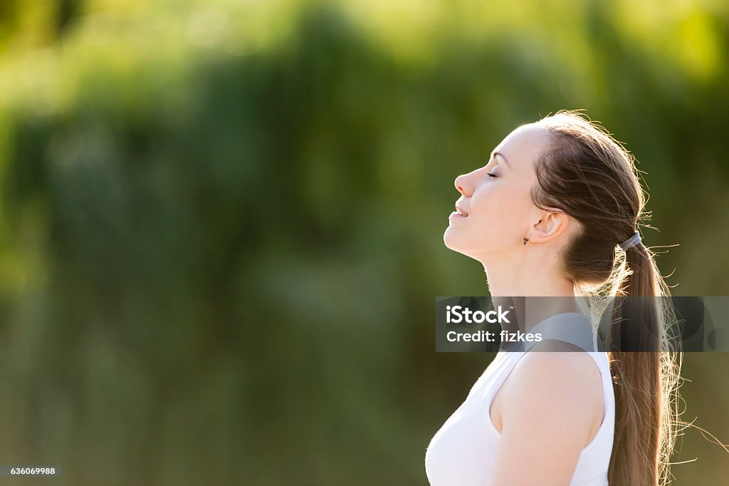 Sporty beautiful smiling young woman relaxing Portrait of beautiful smiling young woman enjoying yoga, relaxing, feeling alive, breathing fresh air, got freedom from work or relations, calm and dreaming with closed eyes, in green park, copy space Breathing Exercise Stock Photo