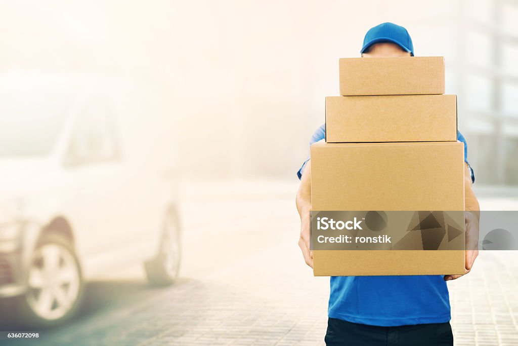 delivery man holding pile of cardboard boxes in front delivery man holding pile of cardboard boxes in front. copy space Delivery Person Stock Photo
