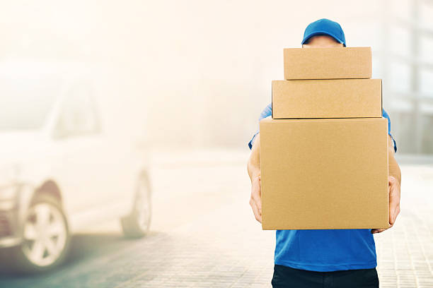 delivery man holding pile of cardboard boxes in front delivery man holding pile of cardboard boxes in front. copy space messenger stock pictures, royalty-free photos & images