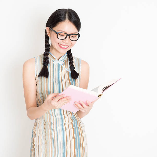 libro di lettura ragazza asiatica - cheongsam chinese culture indoors looking at camera foto e immagini stock