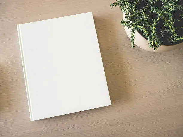 Mock up white Book cover on wooden table with Green Plant