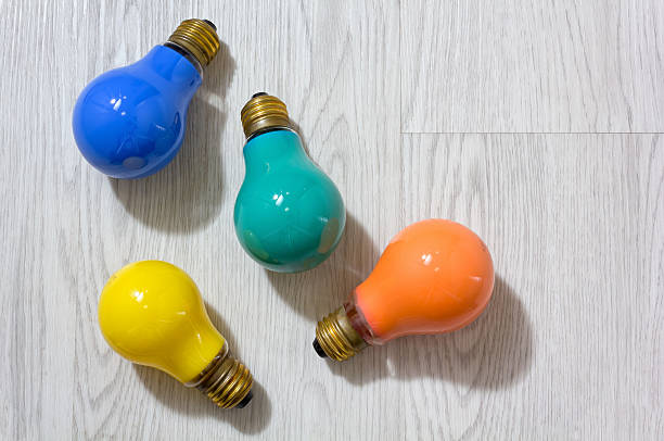 Four Colored Lightbulbs on a Wooden Background stock photo