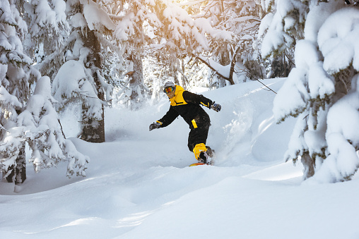 Off-piste snowboarding at ski resort Sheregesh. Snowboarder freerides in forest