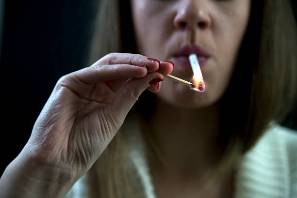istock young brunette woman lighting  a cigarette 636080550