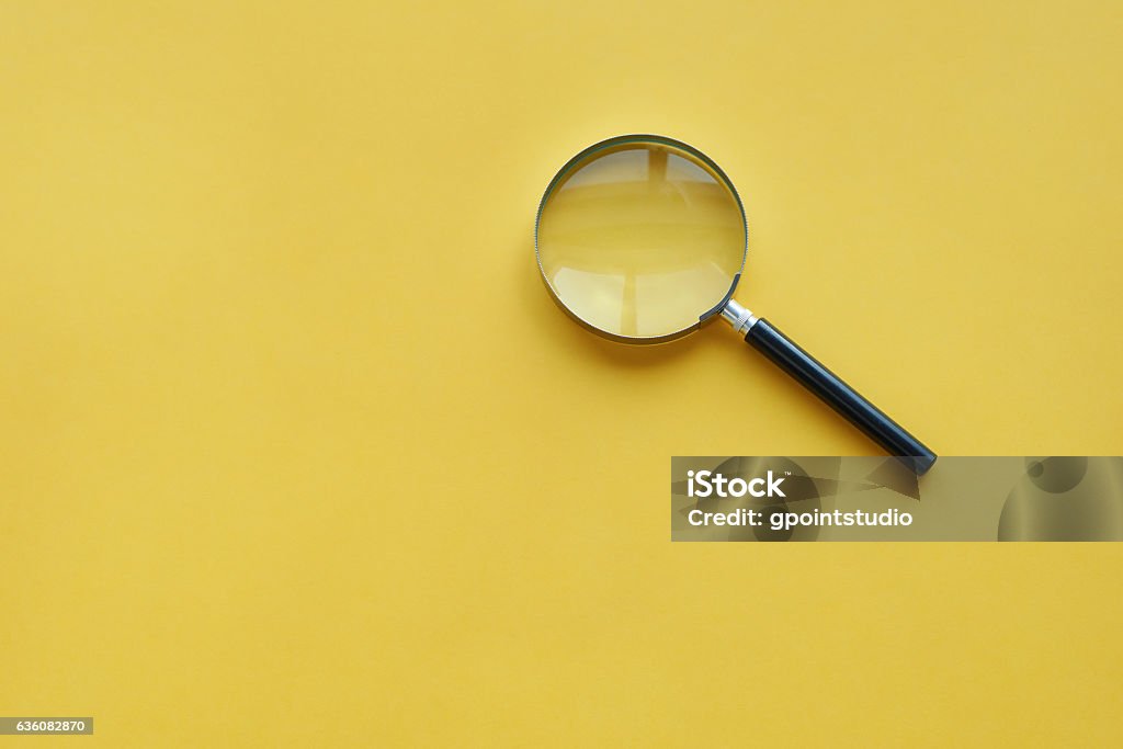 Magnifying glass on the orange background Magnifying Glass Stock Photo