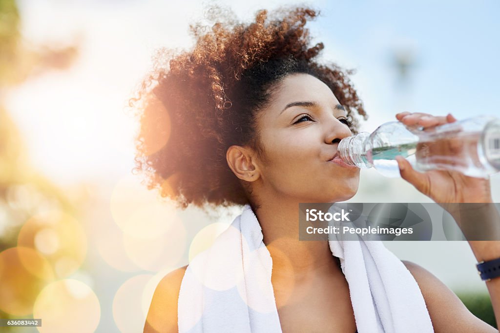 Maintaining good hydration also supports healthy weight loss Cropped shot of a young woman enjoying a bottle of water while out for a run Drinking Water Stock Photo
