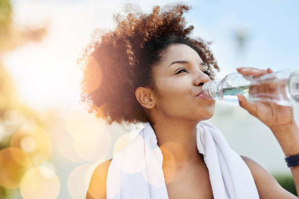 Maintaining good hydration also supports healthy weight loss Cropped shot of a young woman enjoying a bottle of water while out for a run drinking water stock pictures, royalty-free photos & images