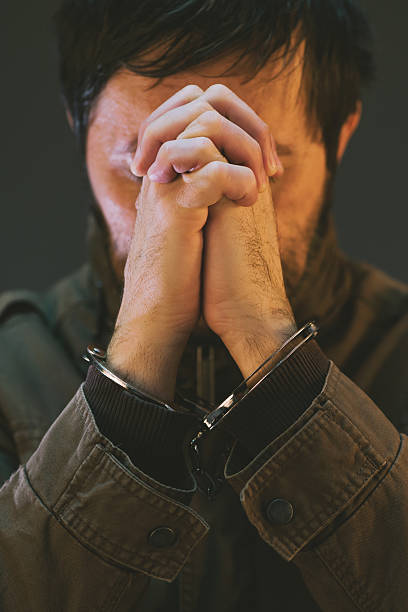 istock Handcuffed male prisoner in military uniform is praying 636087414