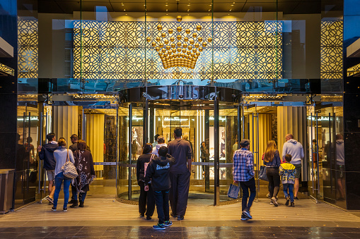 Melbourne, Australia - December 20, 2016: Groups of visitors passing through a entrance to the Crown Melbourne integrated resort in Southbank at dusk.