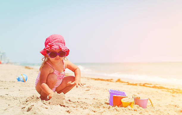 istock cute little girl play with sand on beach 636098692