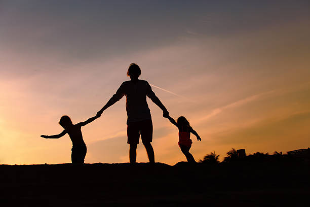 istock father with son and daughter silhouettes play at sunset 636099068