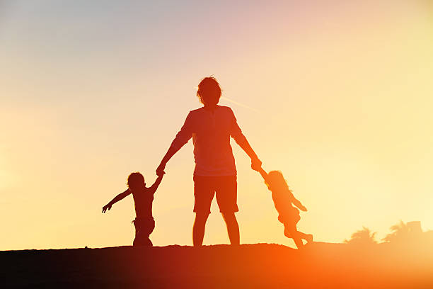 istock father with son and daughter silhouettes play at sunset 636099122