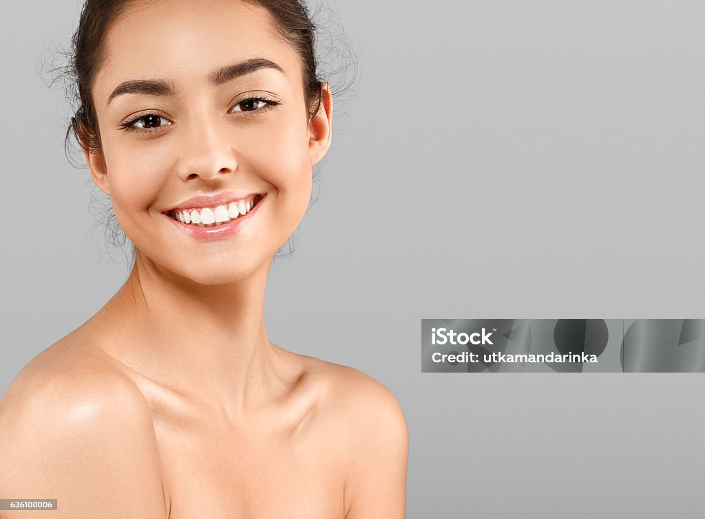 Schönes Gesicht der jungen Frau mit perfekter Haut. Grauer Hintergrund - Lizenzfrei Menschliches Gesicht Stock-Foto