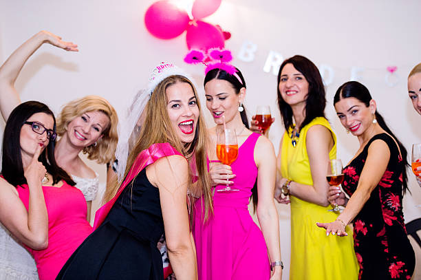 istock Cheerful bride and bridesmaids celebrating hen party with drinks 636102166