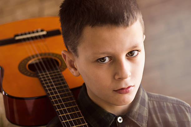 istock Sad Thoughtful Boy With Acoustic Guitar on His Shoulder 636115674