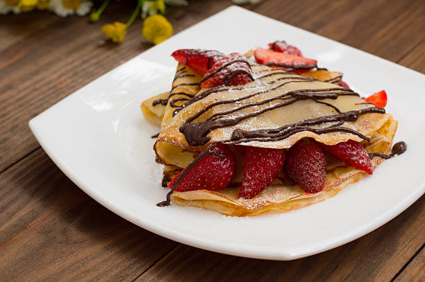 istock Pancakes with strawberries, topped  chocolate. Wooden table. Top view 636117362