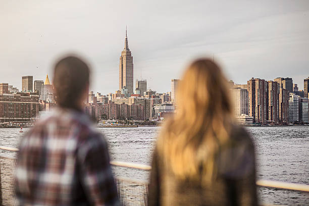 istock Couple looking at Empire State Building by river 636118866