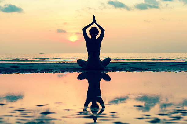 istock Silhouette young woman practicing yoga on the beach at sunset. 636119748