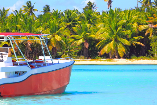 Tropical paradise: turquoise sand beach, lonely yacht ship under Summer blue sky and green palm trees.