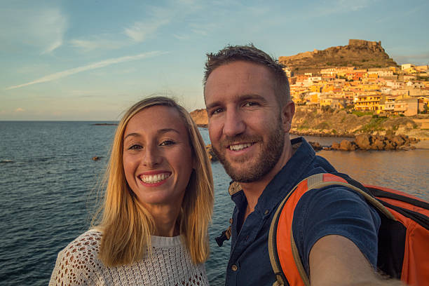 Young couple in Italy take a selfie portrait Young couple in Italy take a selfie portrait with Castelsardo village and seascape on the background. Sunset light, late summer day. castelsardo stock pictures, royalty-free photos & images