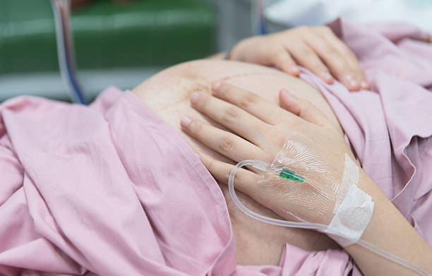 Close up of pregnant woman with IV solution in delivery Close up of pregnant woman with IV solution in delivery room saline drip stock pictures, royalty-free photos & images