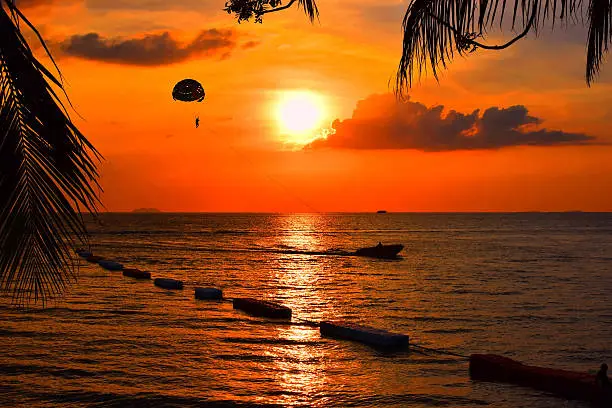 Photo of Playing parachute and boat beside the sea on sunset