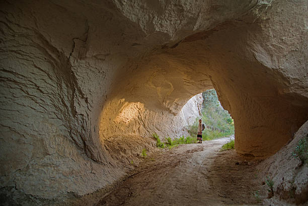 istock woman n sunlit natural rock tunnel 636136002