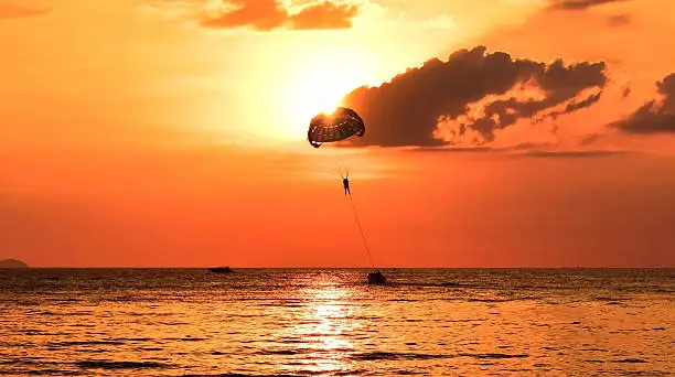 Photo of Playing parachute and boat beside the sea on sunset