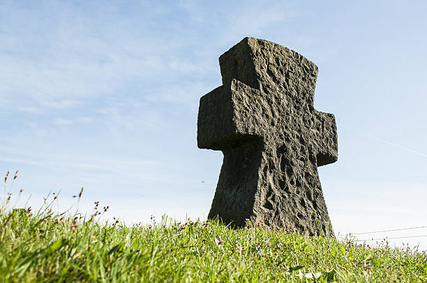 istock Stone cross on grass with a blue sky 636142812