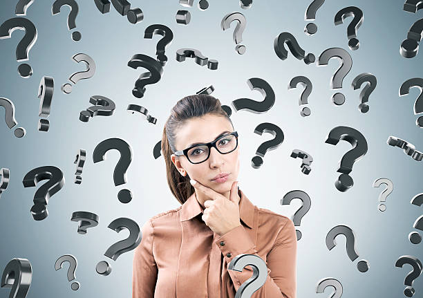 istock Thinking woman and question marks on gray wall 636145720