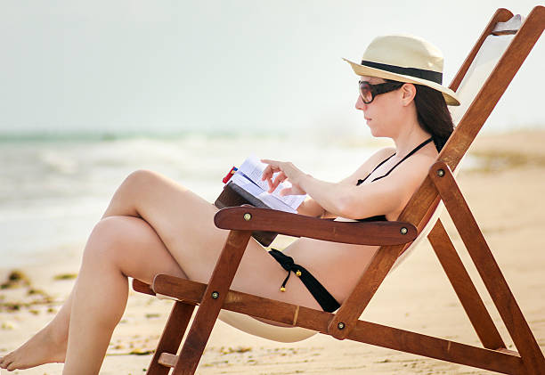 istock Beautiful Woman Reading at Deserted Beach by Sunset 636153724