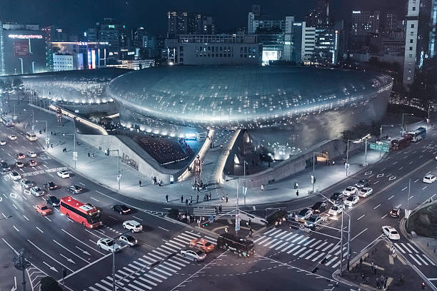 Aerial View Traffic Dongdaemun Design Plaza in Seoul South Korea Seoul, South Korea - October 3, 2016: Aerial View of the Dongdaemun Design Plaza - also called the DDP in Seoul. The DDP is a major urban development landmark in Seoul, South Korea with a distinctively neofuturistic design characterized by the powerful, curving forms of elongated structures. The landmark is the centerpiece of South Korea's fashion hub and popular tourist destination, Dongdaemun, featuring a walkable park on its roofs, large global exhibition spaces, futuristic retail stores and restored parts of the Seoul fortress. Seoul, South Korea, Asia aerial view of seoul south korea capital city stock pictures, royalty-free photos & images