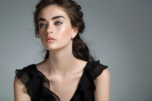 Perfect art woman in black turtleneck on a dark background. Brunette long hair is pulled into a bun. Evening makeup