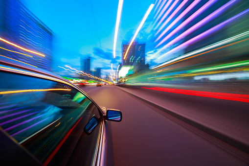 Fast Driving Car Through the City. Long Exposure Photography. Speeding Car Motion Blur