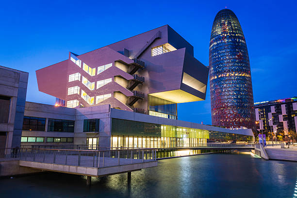 Barcelona, Spain - February 11, 2013: The iconic curves of the Torre Agbar skyscraper overlooking the futuristic decks of DHUB, Disseny Hub Barcelona, the museum and gallery complex on the Placa de les Glories in downtown Barcelona, Spain. 