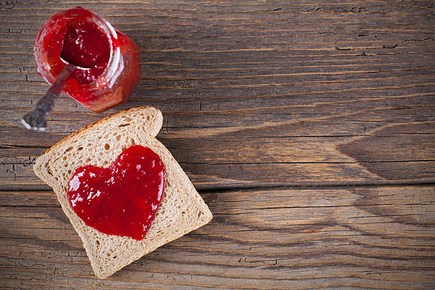 brot und marmelade in herzform auf rustikalem holztisch - toast preserves breakfast bread stock-fotos und bilder