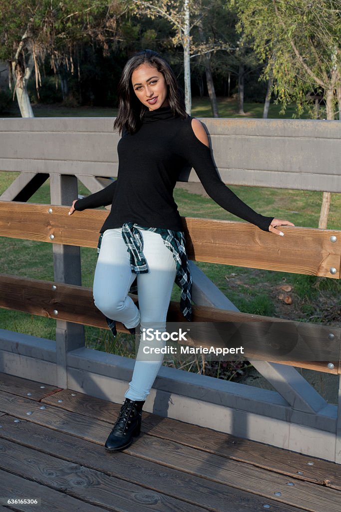 Cover-girl Beautiful female model outside in the park, standing on a bridge.  Adult Stock Photo