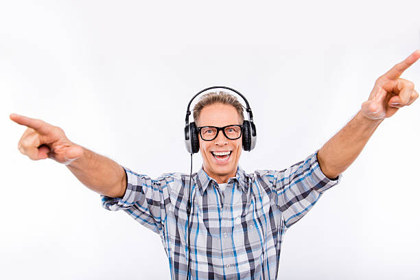 istock Handsome cheerful aged hipster in glasses with headphones raised hands 636170984