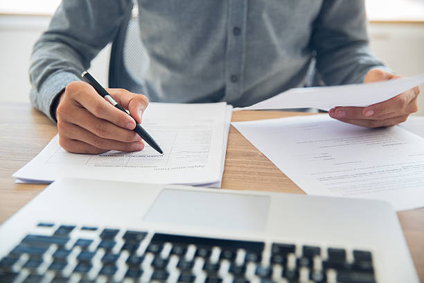 biznesmen sprawdzający dokumenty przy stole - information medium computer men laptop zdjęcia i obrazy z banku zdjęć